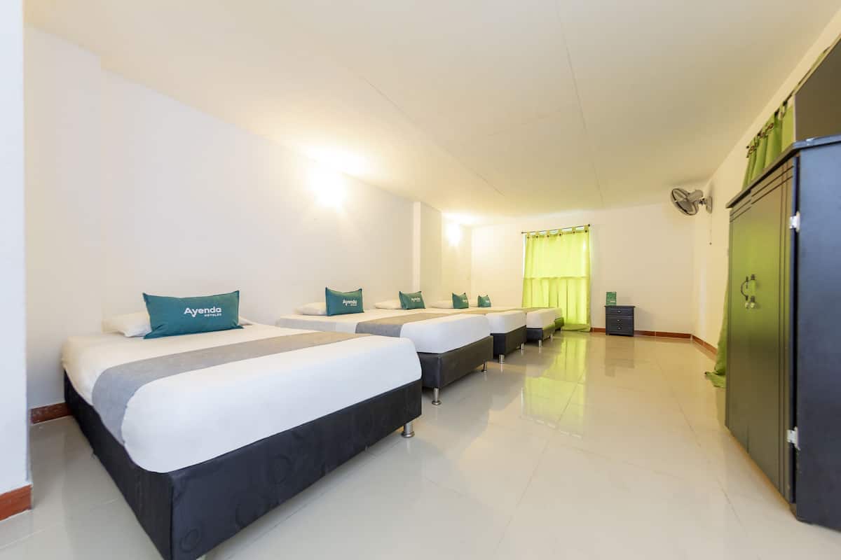 Una habitación de hotel con tres camas, cada una con un almohadón que dice "Ayenda".