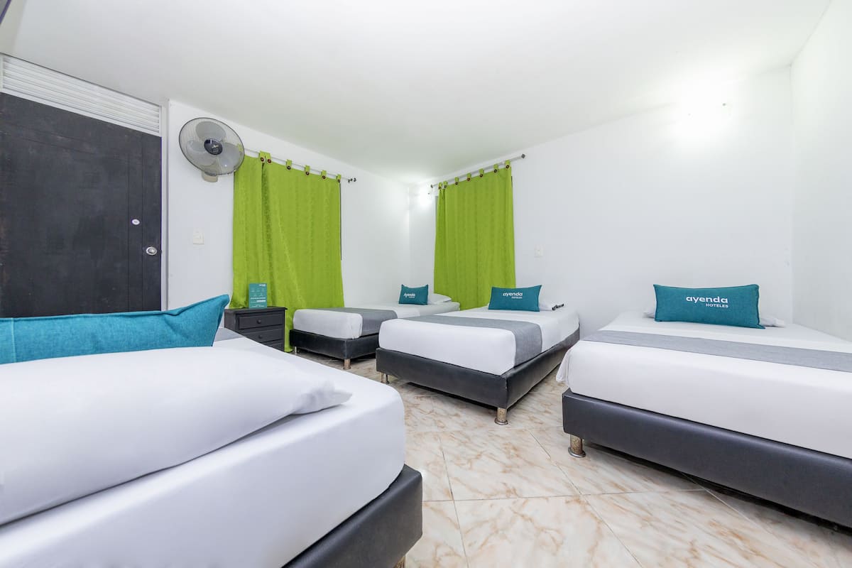 Habitación de hotel con tres camas, un ventilador y cortinas verdes.