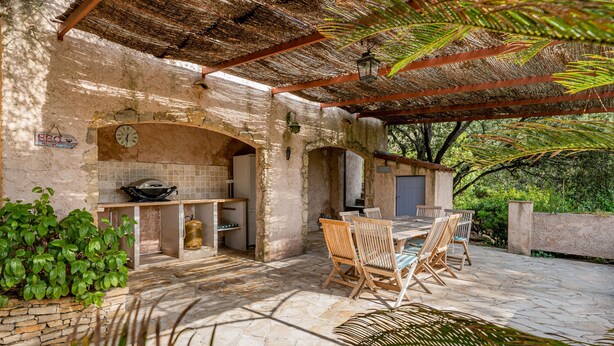 An outdoor patio with stone flooring, wooden furniture, and a brick oven. - Villa Dourmidou · Heated pool · Bandol wine region · Near beaches (La Cadière-D'azur)