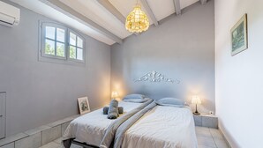 A bedroom with a bed, bedside lamps, a decorative wall piece, and a window. - Villa Dourmidou · Heated pool · Bandol wine region · Near beaches (La Cadière-D'azur)