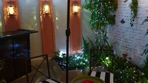 An outdoor patio area with a striped umbrella, two chairs, a small table, and decorative lights. - Perfect Place and Breakfast Too! (Pittsburgh)