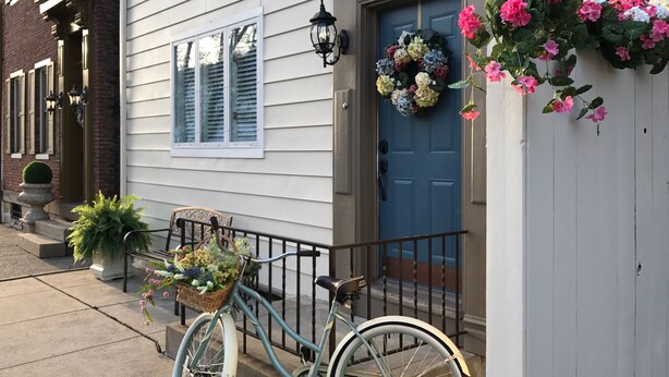 A townhouse with a blue front door, a number plaque, a front porch with a bench, and a bicycle with a basket of flowers. - Perfect Place and Breakfast Too! (Pittsburgh)