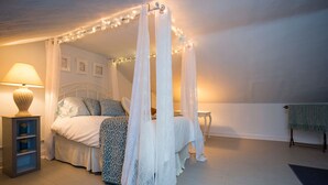 A bedroom with a four-poster bed, a bedside table with a lamp, and a small shelf. - Perfect Place and Breakfast Too! (Pittsburgh)