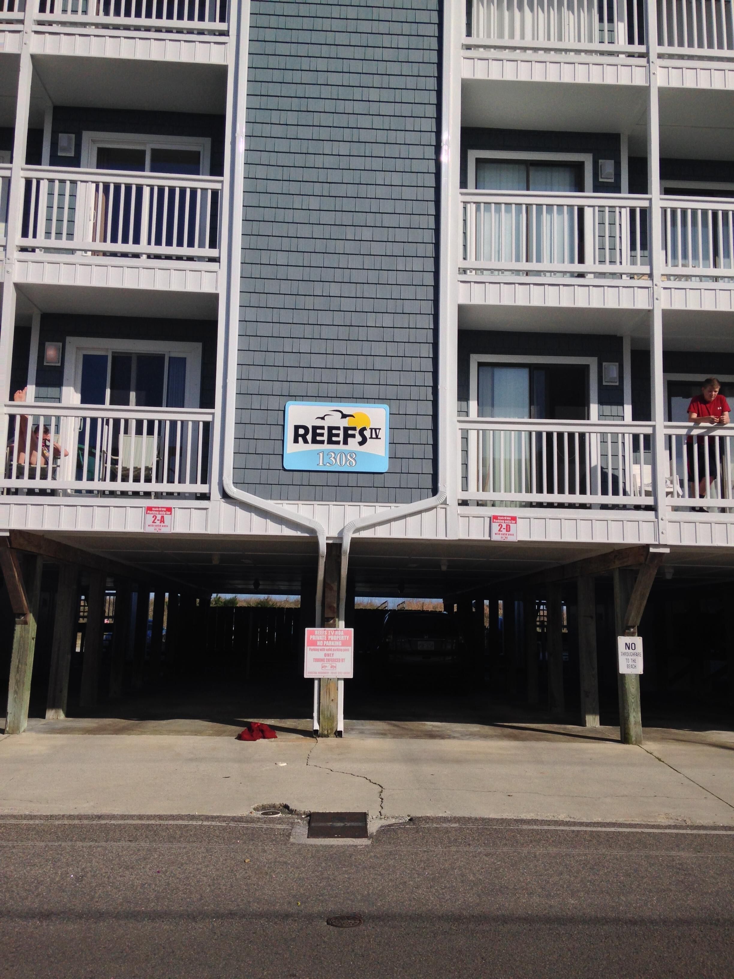 A multi-story building with balconies, a sign reading "REEFS IV 1308", and a no parking sign.
