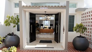 A modern villa entrance with a sign reading "Villa Maxine," a reception desk, and potted plants. - Villa Maxine Retreat: Mountainview Pool Near San Juan Airport (Guaynabo)