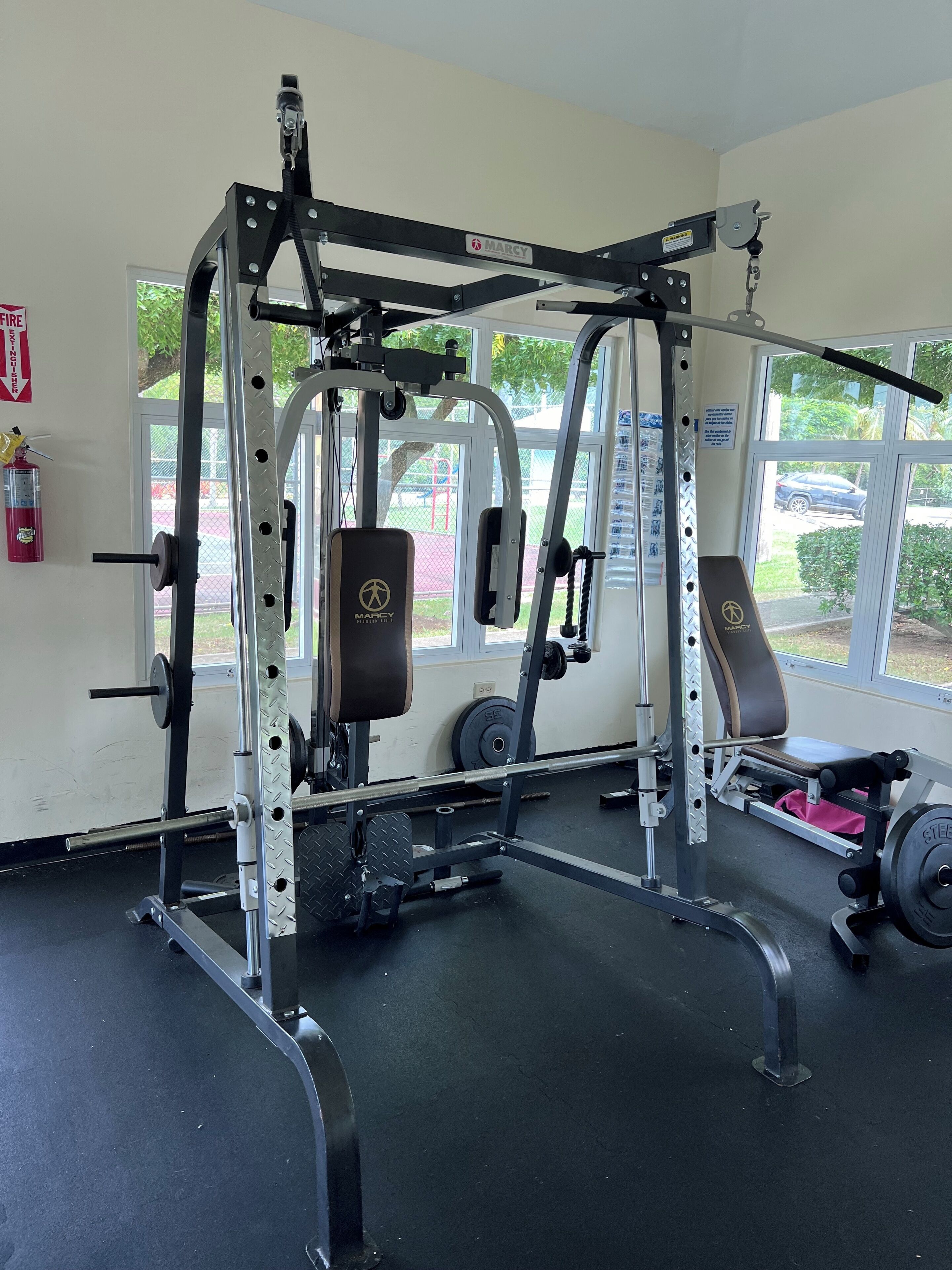 A gym with a multi-functional workout station, weight racks, and benches.