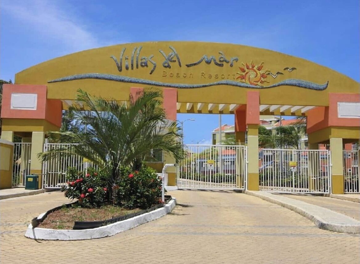 The entrance to Villalba Mar Beach Resort with a yellow archway and a gated driveway.
