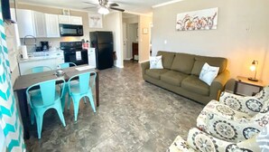 A living room with a sofa and chairs, a dining area with a table and chairs, and a kitchen with appliances. - The Lorena Ranchette- Goats, Firepit, Hammock (Lorena)
