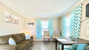 A living room with a sofa, chairs, a dining table, and patterned curtains. - The Lorena Ranchette- Goats, Firepit, Hammock (Lorena)