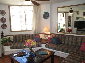 A living room with a sofa, a coffee table, a lamp, and a television.