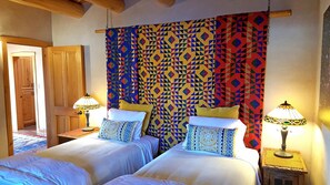 A room with two beds, a patterned headboard, and two lamps.