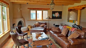 A cozy living room with leather furniture, a fireplace, and a large window.