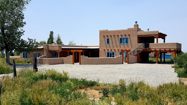 A modern house with a flat roof, multiple windows, and a gravel driveway.