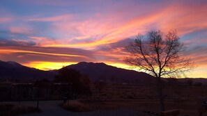 A landscape with mountains, a tree, and a sunset.