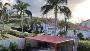 Un espace extérieur abrité, doté d’un toit rouge, entouré d’une clôture en bois et agrémenté d’un banc.