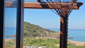 Un balcón con vista al mar, un tejado de tejas rojas y una pérgola de madera.