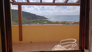 Un balcón con vista al mar y las colinas.