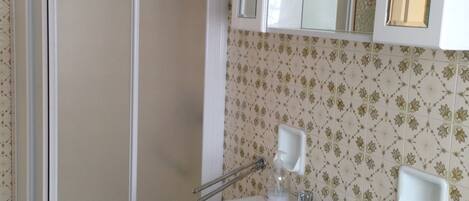 Une salle de bain avec une douche, un lavabo avec un miroir et des toilettes.