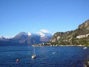 Un paysage côtier avec un voilier, un ciel bleu dégagé et des montagnes en arrière-plan.