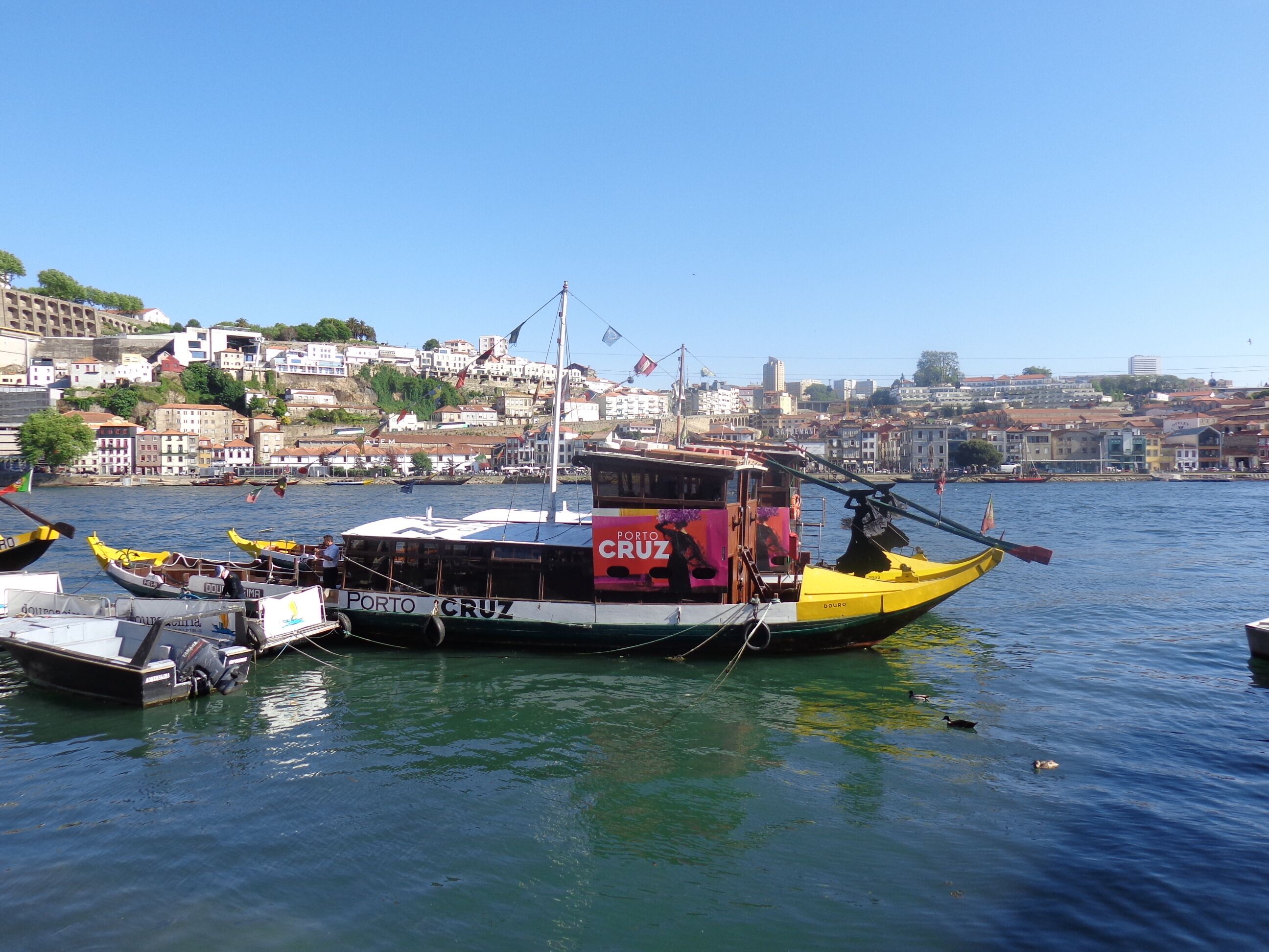 A harbor with boats docked, a large ship named 'PORTO CRUZ', and a cityscape in the background.