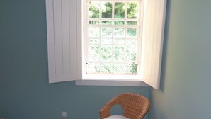 A room with a window, a wicker chair, and a patterned floor. - Apartment in the Ribeira 10 meters from the river, in the heart of the city (Porto)