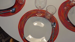 A round dining table with a white plate, a spoon, and a glass on a colorful striped placemat. - Apartment in the Ribeira 10 meters from the river, in the heart of the city (Porto)