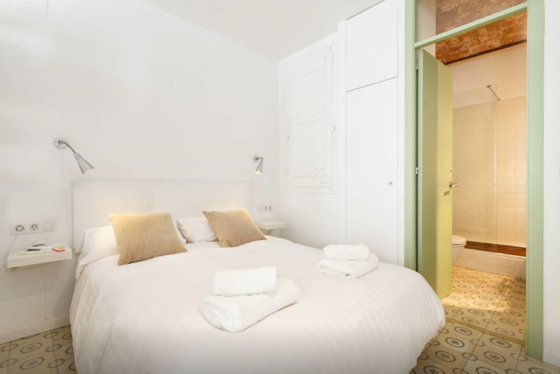 Habitación de hotel con una cama grande, dos mesitas de noche y un baño visible a través de una puerta abierta.