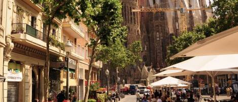 A street with outdoor cafes, trees, and historic buildings in the background.