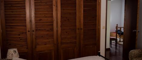 A bedroom with a large wooden wardrobe, a bed, and a chair.