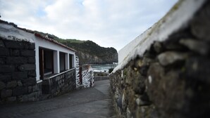 Un estrecho sendero de piedra que lleva a un edificio blanco con ventanas, con vistas a una zona costera con acantilados.
