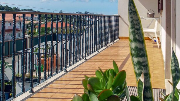 A balcony with a wooden floor, metal railing, and potted plants. - House in quiet area of ​​housing. But close to the center. (Sintra)