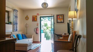 A living room with a sofa, a chair, a table, a lamp, and a view of the outside. - House in quiet area of ​​housing. But close to the center. (Sintra)
