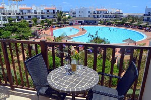 Un área de piscina con varias piscinas, sillones de descanso y sombrillas.