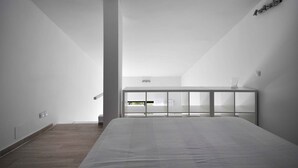 Een moderne slaapkamer met een groot bed, een glazen scheidingswand en een klein balkon.