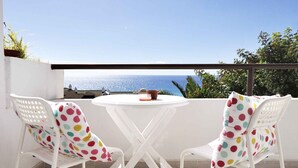 Een terras met twee witte stoelen en een tafel, met uitzicht op een prachtig panorama.