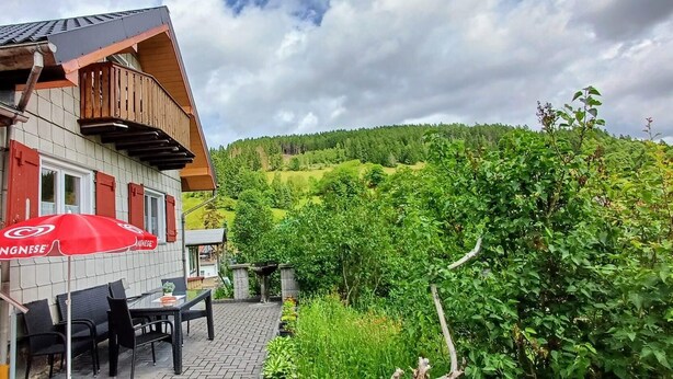 A building with a balcony, outdoor seating, and a view of a green hillside. - Vacation hut on the Goethe Trail with a view, close to the Rennsteig, UNESCO biosphere reserve (Ilmenau)