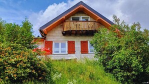A two-story house with a wooden balcony, surrounded by lush greenery. - Vacation hut on the Goethe Trail with a view, close to the Rennsteig, UNESCO biosphere reserve (Ilmenau)