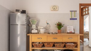 Een moderne keuken met een roestvrijstalen koelkast, een weegschaal, een waterkoker en een klok aan de muur.
