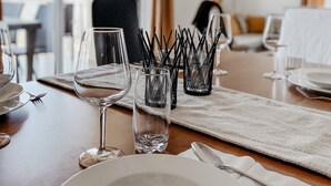 Une table à manger dressée avec de l’assiette blanche, des verres et des couverts, ainsi qu’un set de table en fibres tressées.