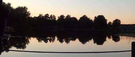 A calm lake at sunset with trees reflected in the water.