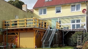 A two-story house with a red-tiled roof, a wooden deck, and a garage.