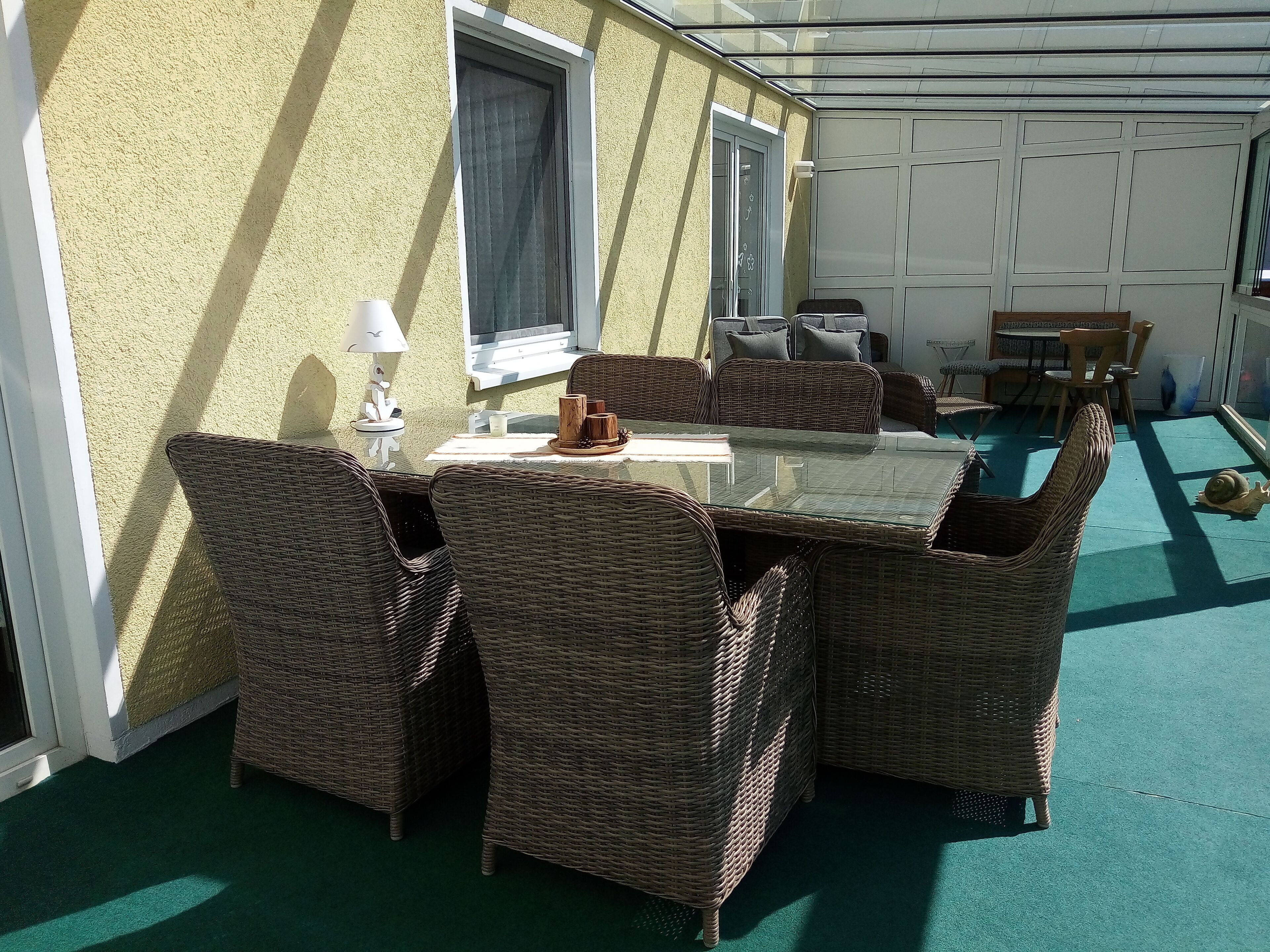 Eine Terrasse im Freien mit Korbmöbeln, einem Tisch und Stühlen.