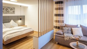 Un dormitorio moderno con una cama, un sofá y una mesita con un florero.