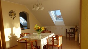 A dining area with a table set for six, a clock on the wall, and a skylight above. - Experience nature - enjoy peace (Mohlsdorf-Teichwolframsdorf)