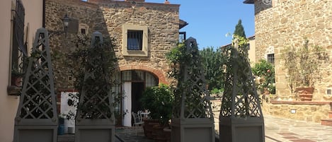 Une rue étroite bordée d’immeubles en pierre, un portail avec une grille en métal et un petit escalier menant à une porte.