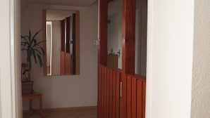 Ein Flur mit Holzboden, einem Blumentopf, einem Spiegel und einer Tür zu einem anderen Raum.