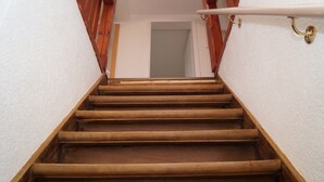 Eine Holztreppe mit einer weißen Wand auf einer Seite und einem Holengeländer auf der anderen.