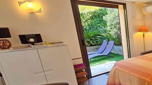 Hotelkamer met een bed, een bureau, een stoel, een kledingkast en een deur naar een buitenruimte met een glijbaan.
