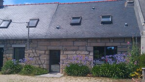 A stone building with a sloped roof, multiple windows, and a small door. - Penmarc’h-Holiday Cottage (Penmarch)