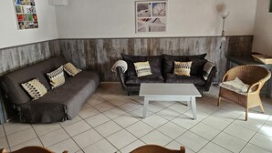 Ein Wohnzimmer mit zwei dunklen Sofas, einem weißen Couchtisch und einem Korbstuhl.